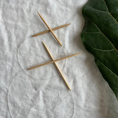 Two bamboo circular knitting needles on white background.