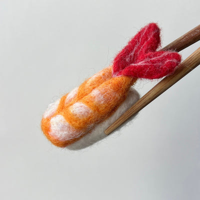 Felted sushi with wooden chopsticks on a light gray background
