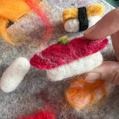 Handmade felted sushi with colorful elements on a textured surface