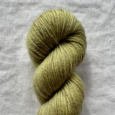 Skein of green yarn on a gray fabric background