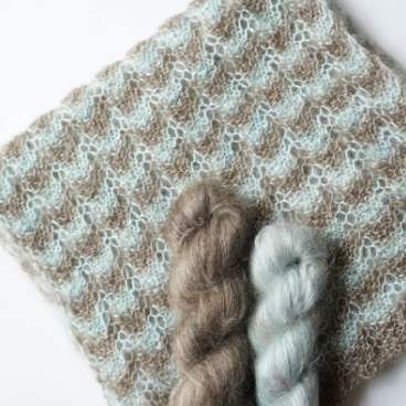 Two skeins of yarn on a knit scarf