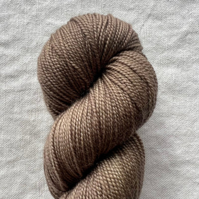 Taupe skein of yarn on a textured gray background