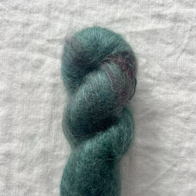 Teal skein of yarn on a textured white background