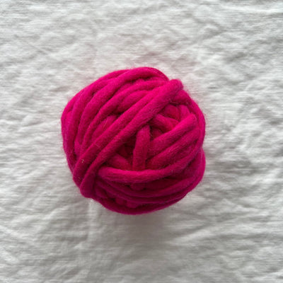 Ball of pink yarn on a textured white background