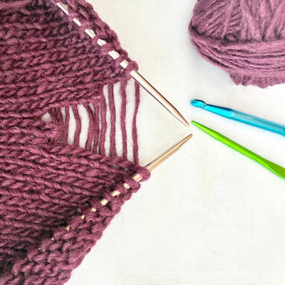 Knitted fabric with knitting needles and yarn on a white background