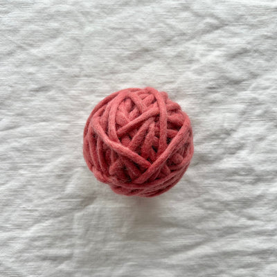 Ball of pink yarn on a textured gray background