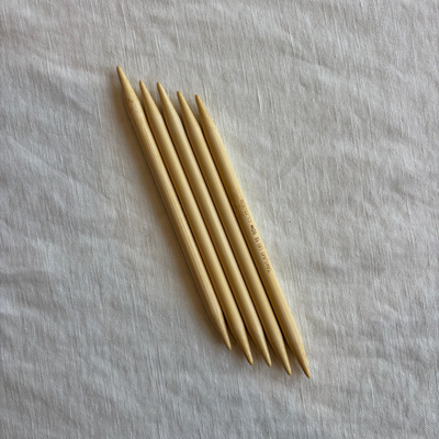 Set of wooden knitting needles on a light fabric background