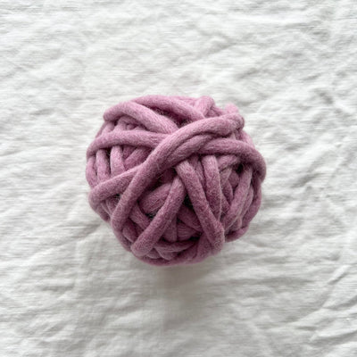 Pink ball of yarn on a textured white surface