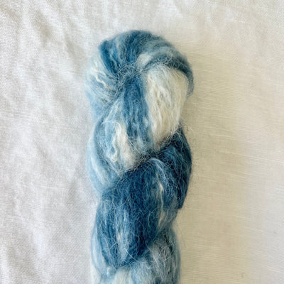 Blue and white skein of yarn on a textured white background