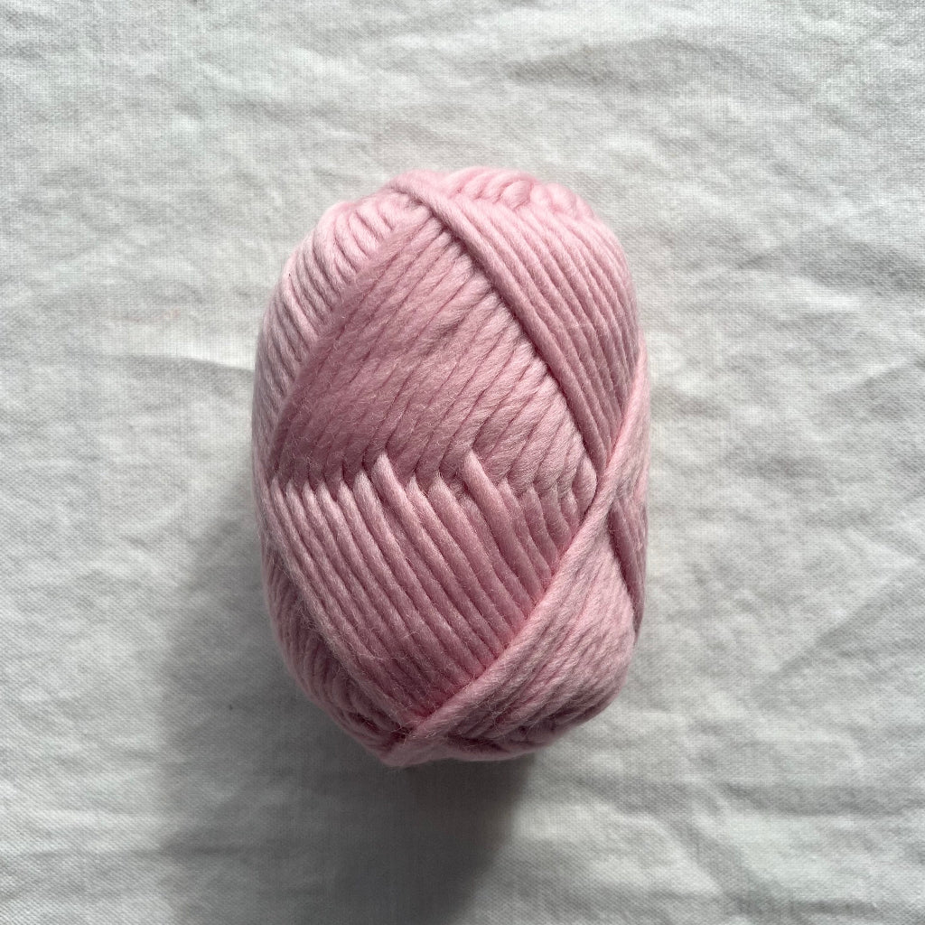 Pink skein of yarn on a gray fabric background