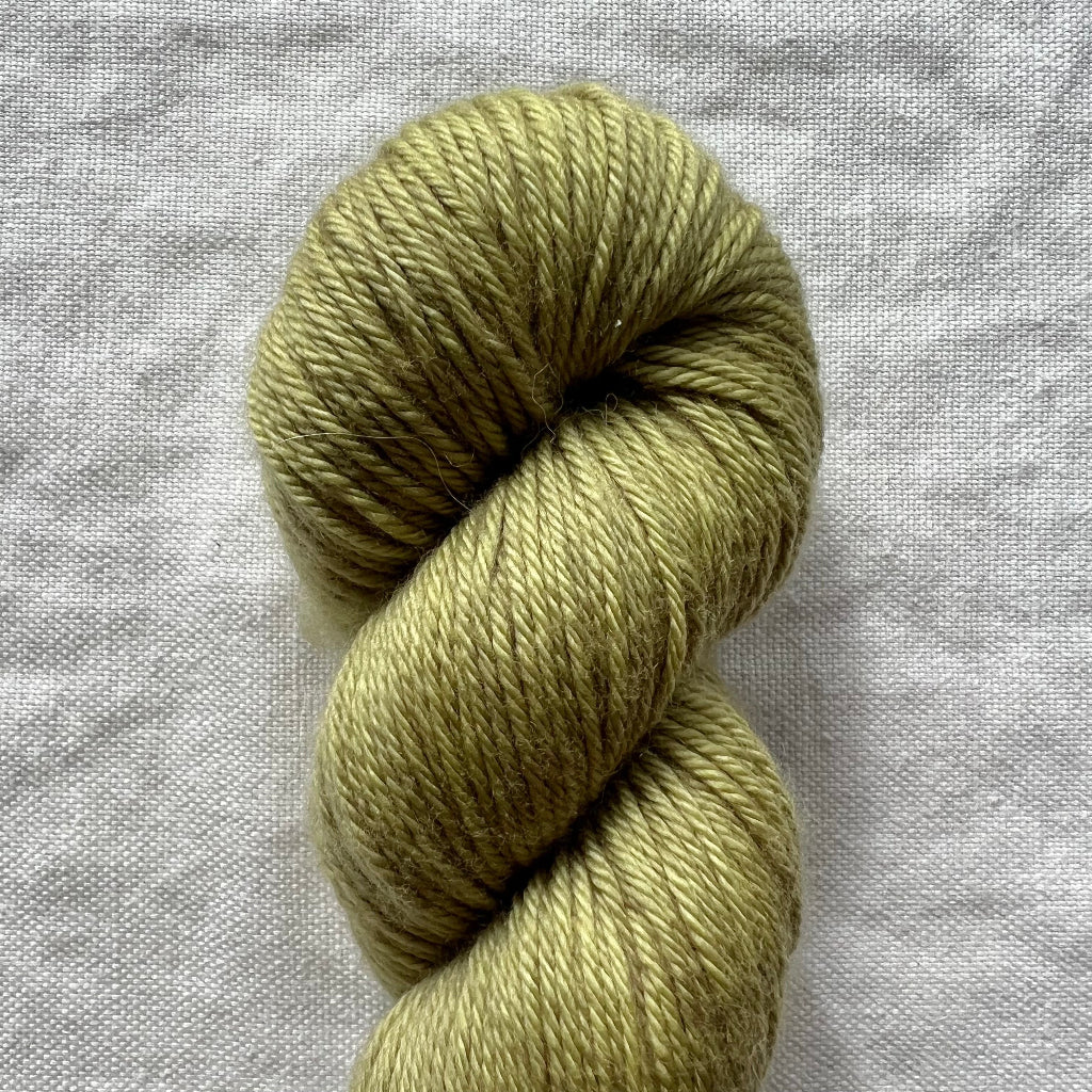 Skein of green yarn on a gray fabric background