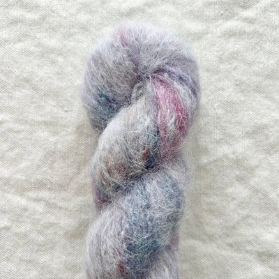 Blue and purple skein of yarn on a textured white background