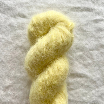 Yellow skein of yarn on a white fabric background