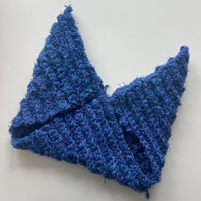 Blue textured fabric folded into a triangle shape on a light gray background
