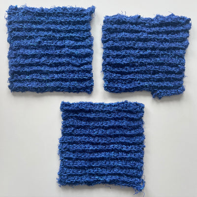 Three blue crocheted squares on a white background
