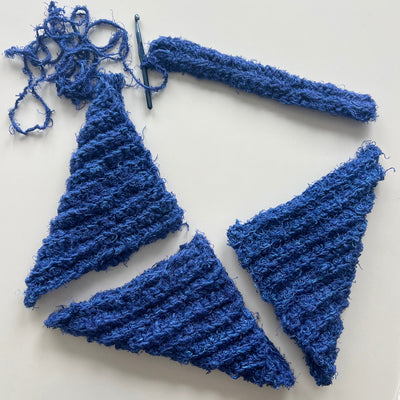 Blue knitted triangles with a crochet hook on a white background