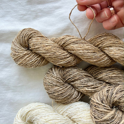 Three skeins of yarn in natural colors on a light surface