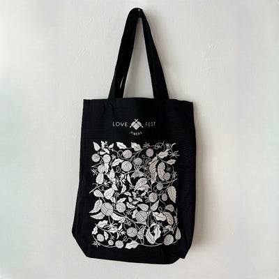 Black tote bag with white floral design and text on a light gray background
