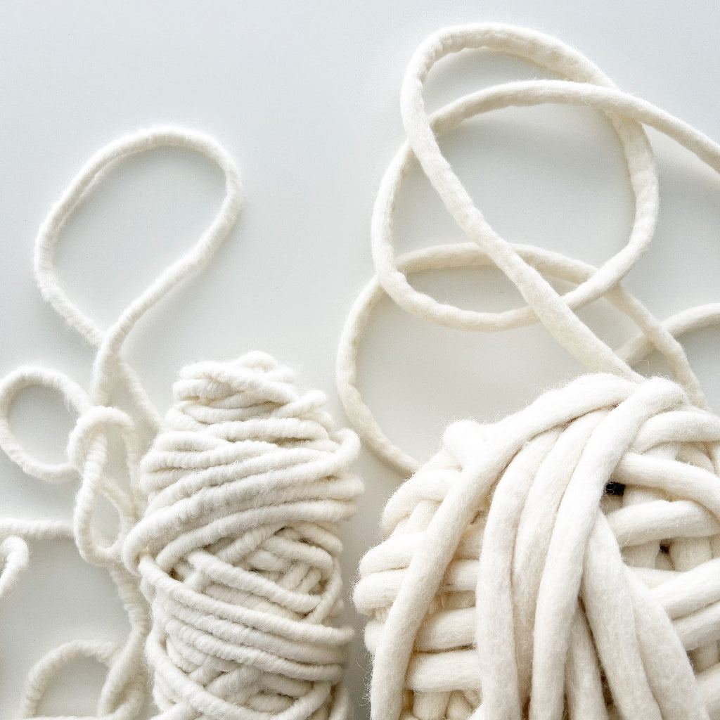 Two bundles of white yarn on a light  background