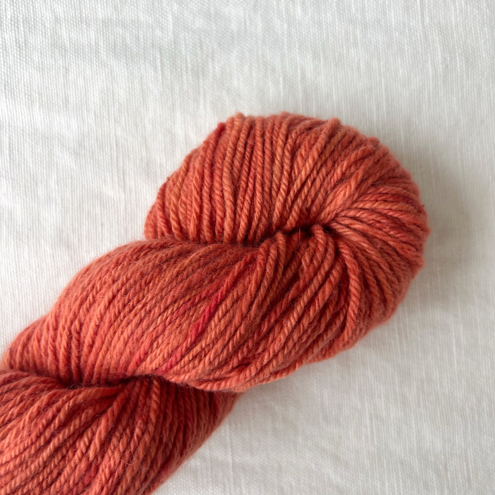 Ball of red yarn on a white fabric background