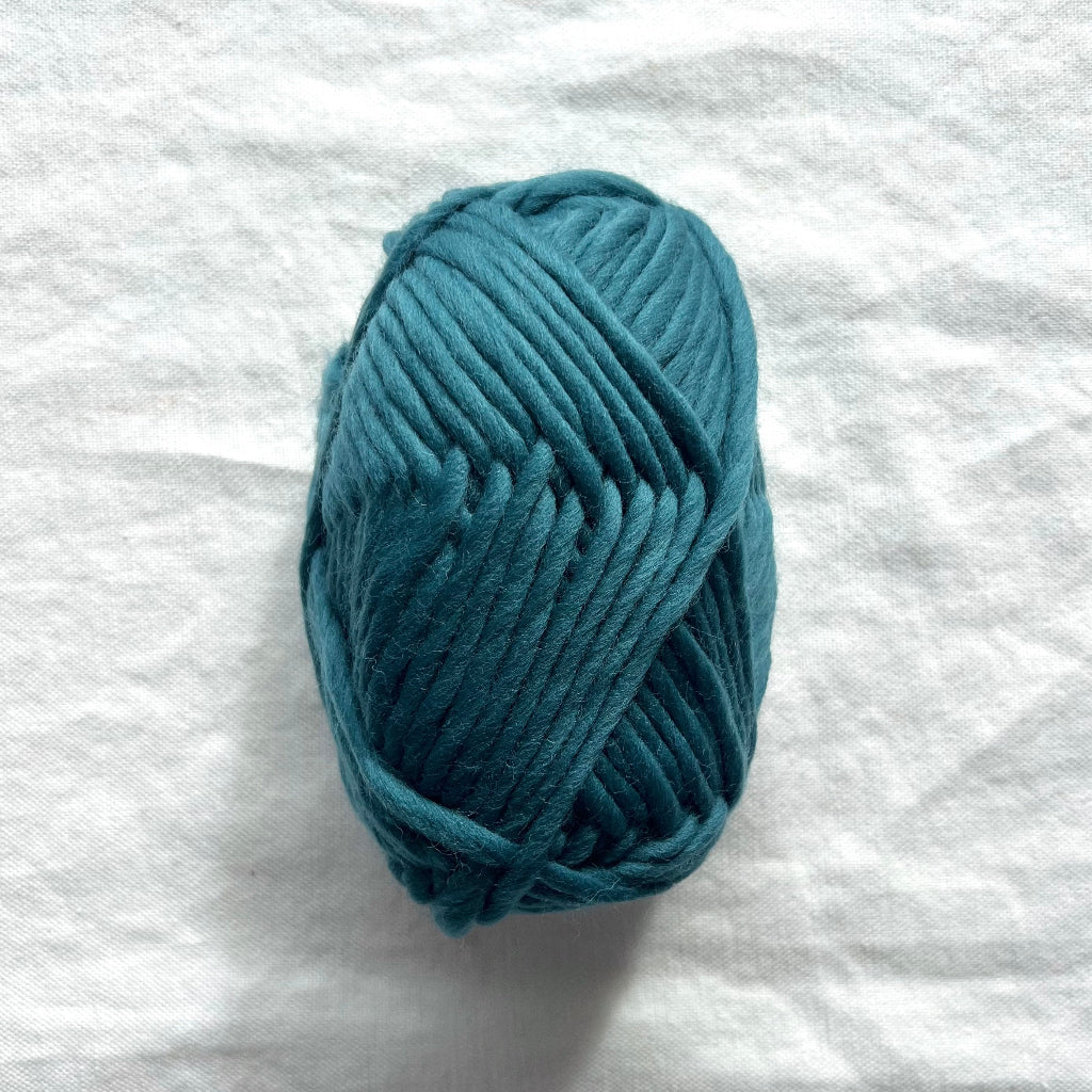 Blue skein of yarn on a white fabric background