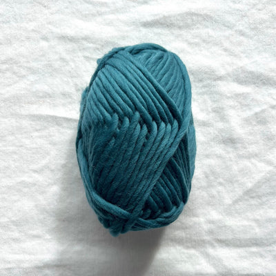 Blue skein of yarn on a white fabric background