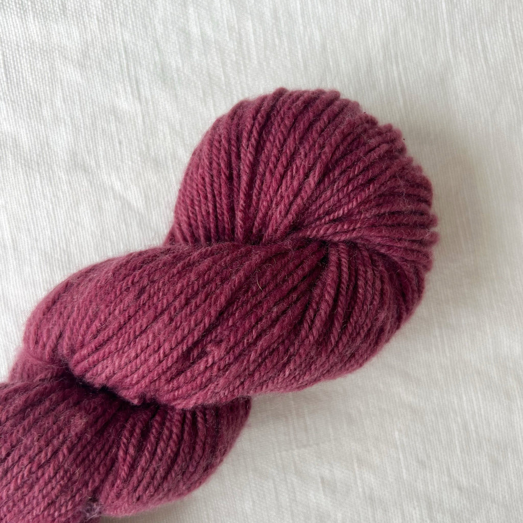 Ball of dark pink yarn on a light gray background