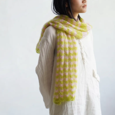 Person wearing a green and pink checkered scarf on a white background