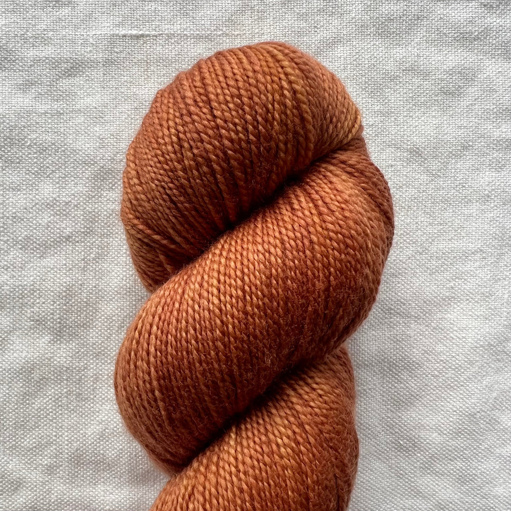Brown skein of yarn on a light gray fabric background