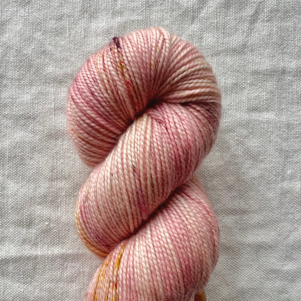 Pink skein of yarn on a textured gray background
