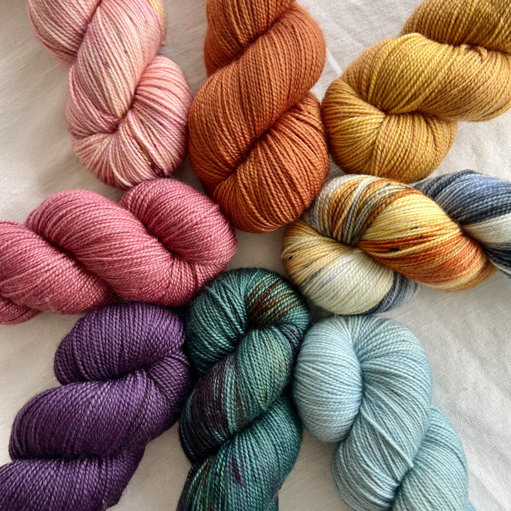 Assorted skeins of yarn in various colors on a light background