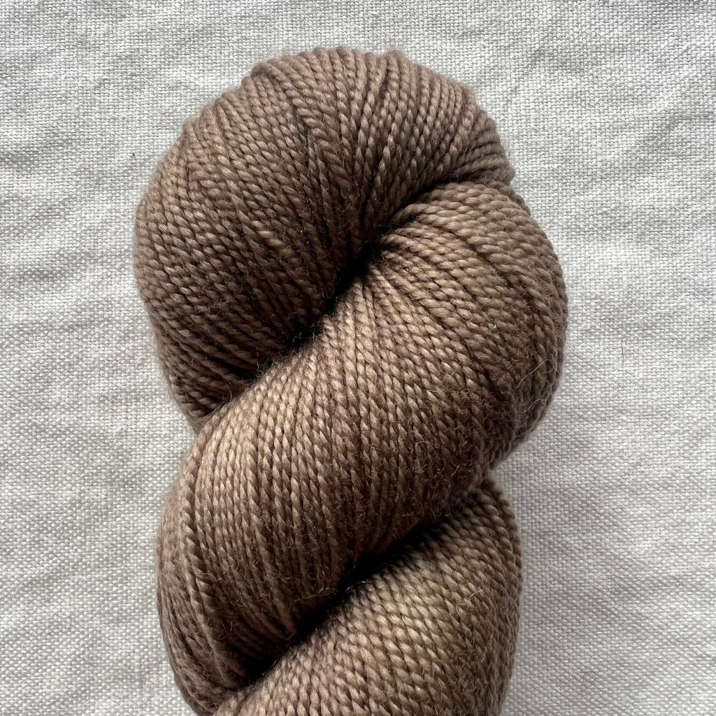 Taupe skein of yarn on a textured gray background