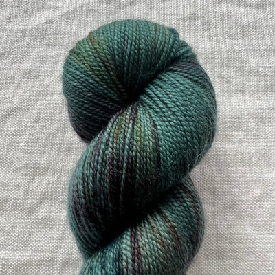 Skein of green yarn on a textured gray background