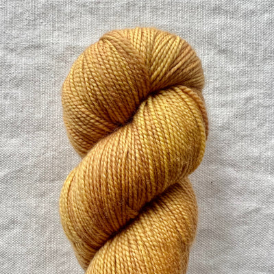 Ball of gold yarn on a gray fabric background
