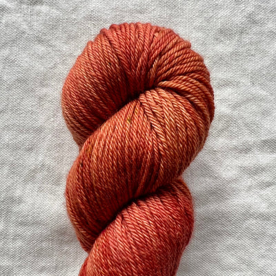 Skein of rust-colored yarn on a textured gray background