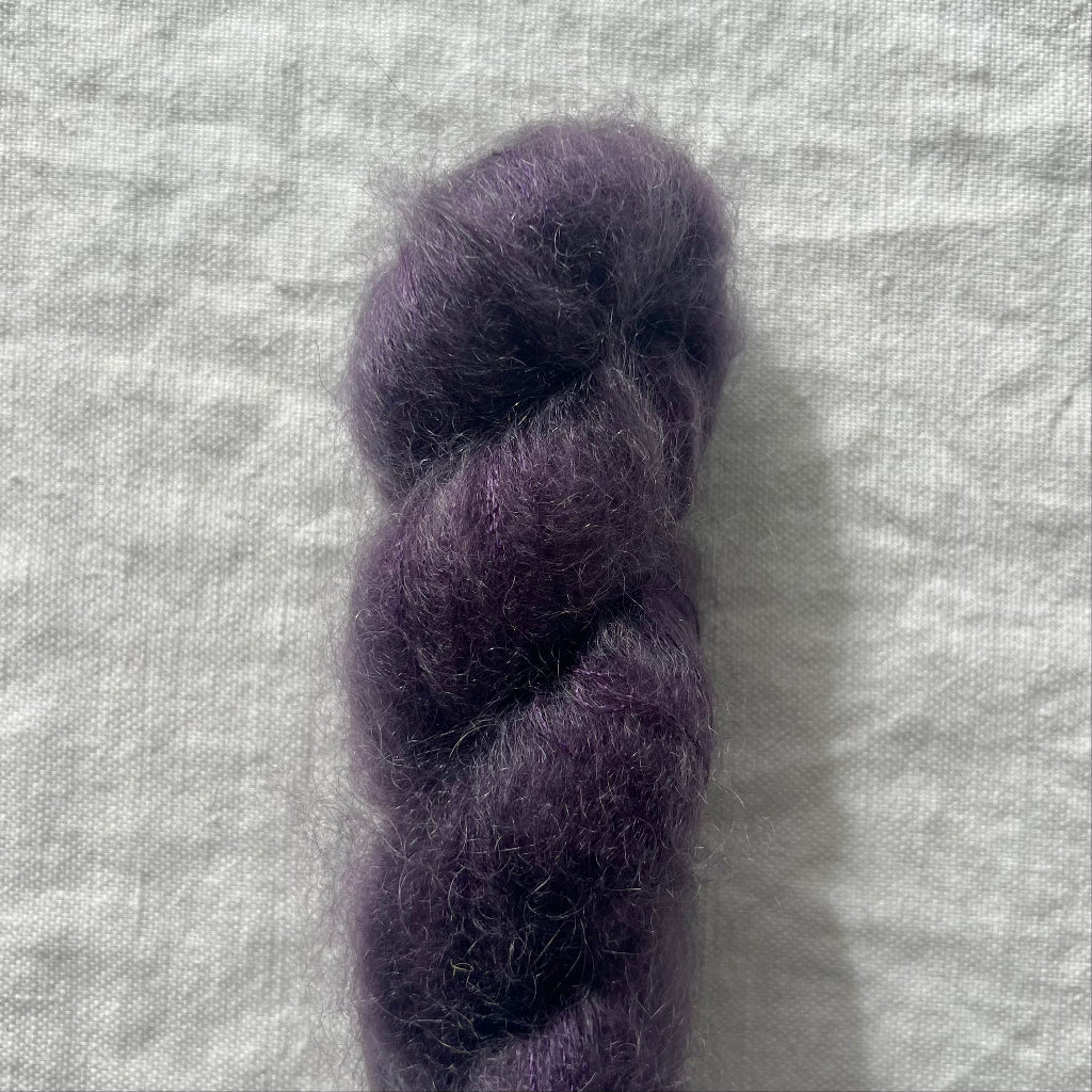 Purple skein of yarn on a textured gray background