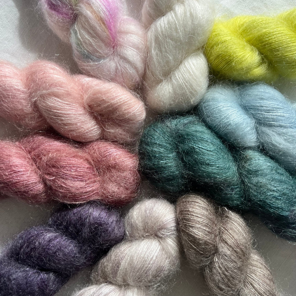 Assorted skeins of yarn in pastel colors on a light background