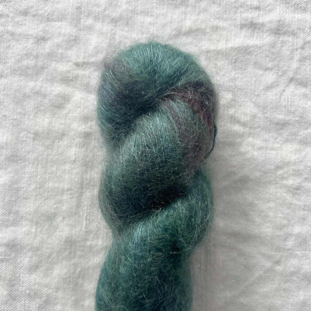 Teal skein of yarn on a textured white background