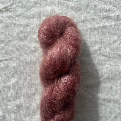 Skein of dark pink yarn on a textured gray background