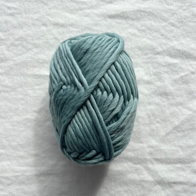 Light blue skein of yarn on a white fabric background