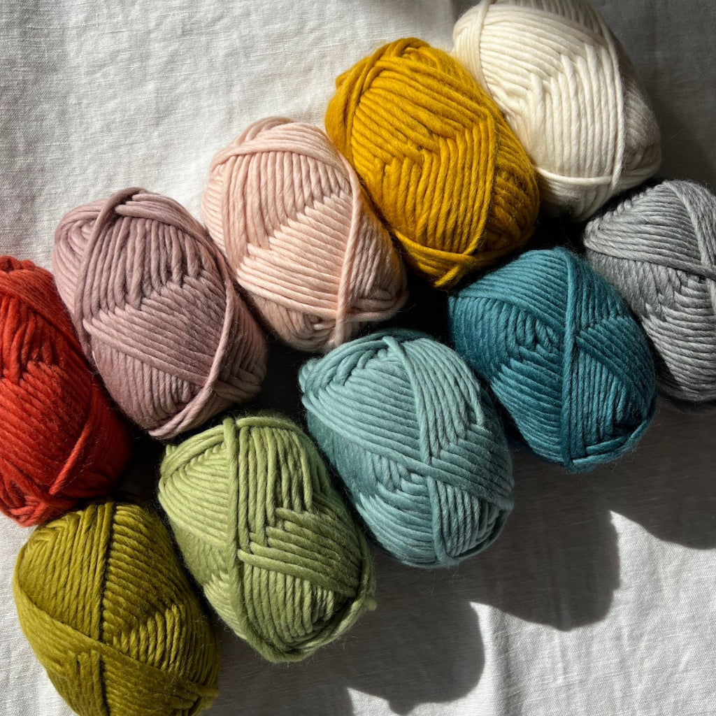 Assorted colorful yarn balls on a white fabric background
