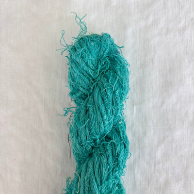Turquoise yarn skein on a textured white background