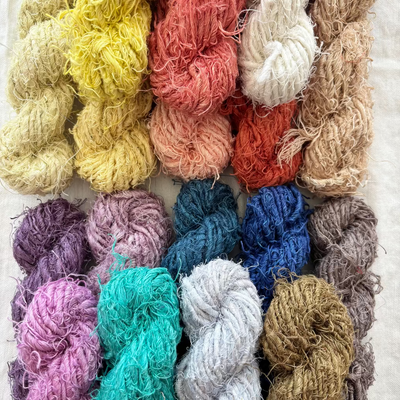 Assorted colorful yarn skeins arranged in a grid on a light background