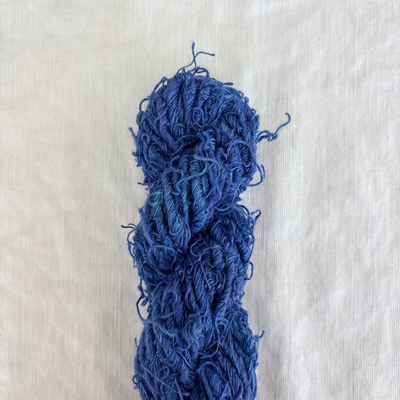 Blue skein of yarn on a light beige fabric background