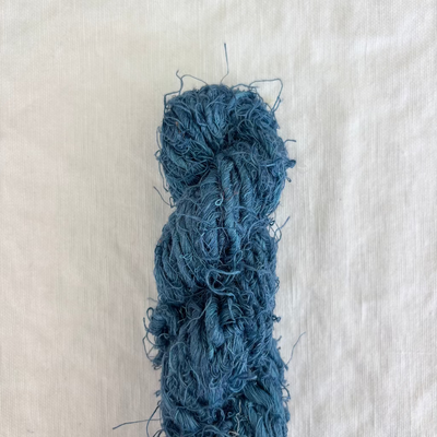 Blue skein of yarn on a light beige fabric background