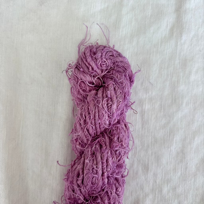 Purple skein of yarn on a light beige background