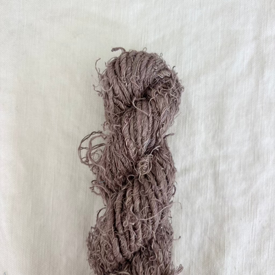 Brown skein of yarn on a textured beige background