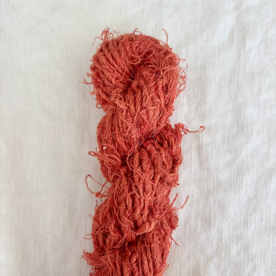 Red yarn skein on a textured beige background
