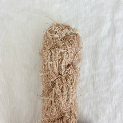 Ball of beige yarn on a light beige background