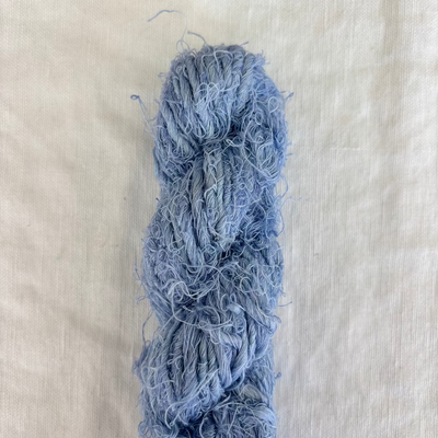 Blue skein of yarn on a white fabric background